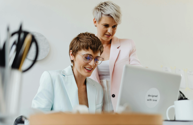 Zwei Frauen arbeiten zusammen am Computer in einem modernen Büroumfeld.