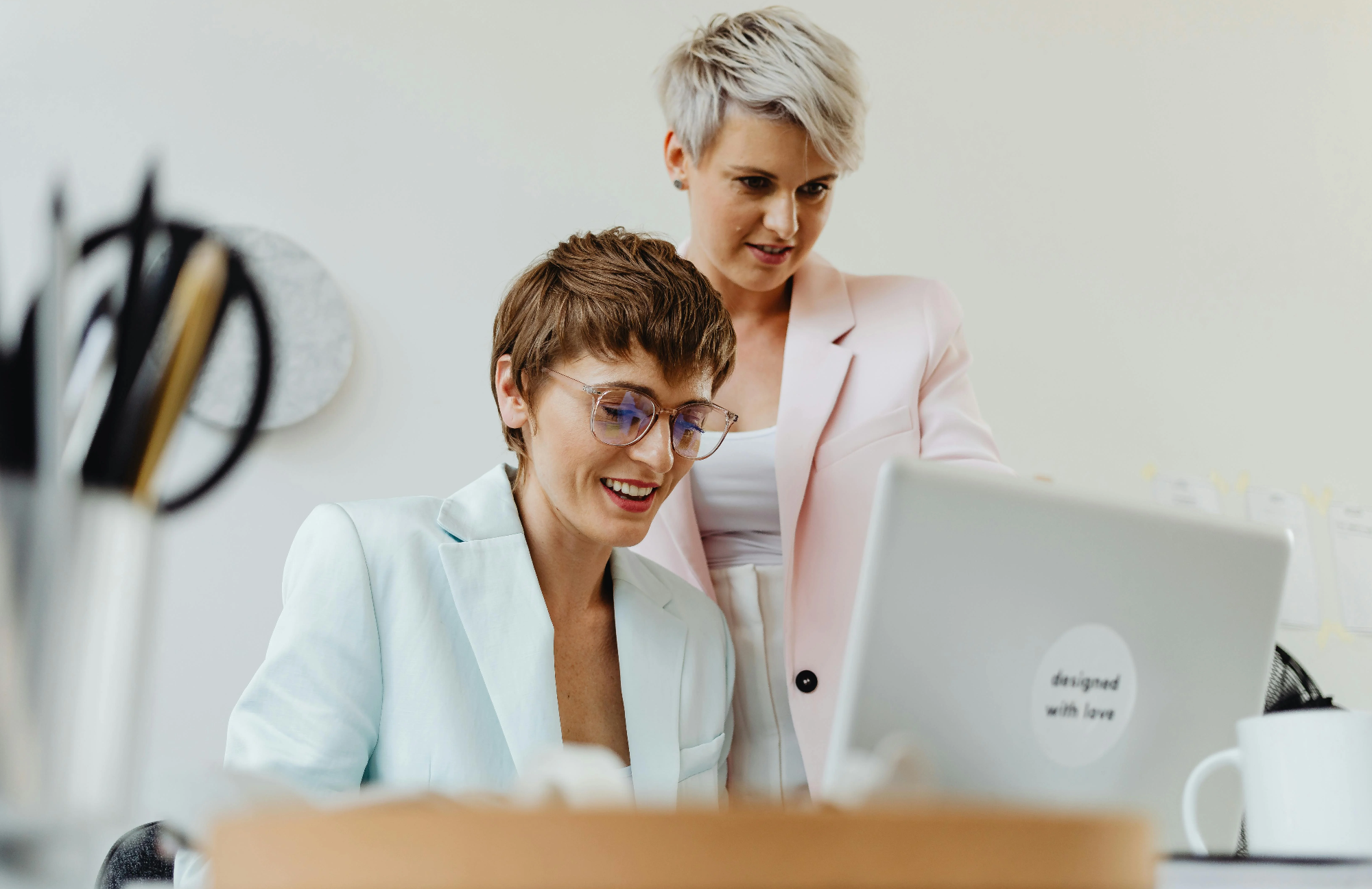 Zwei Frauen arbeiten zusammen am Computer in einem modernen Büroumfeld.