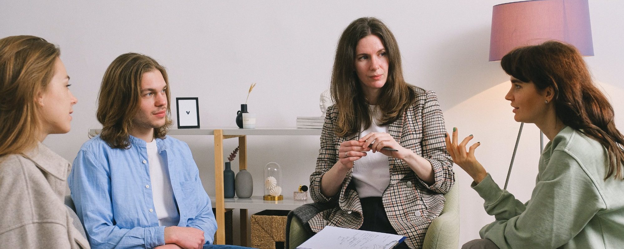 Vier Frauen sitzen in einem Gespräch, eine zeigt etwas auf ihrer Hand.