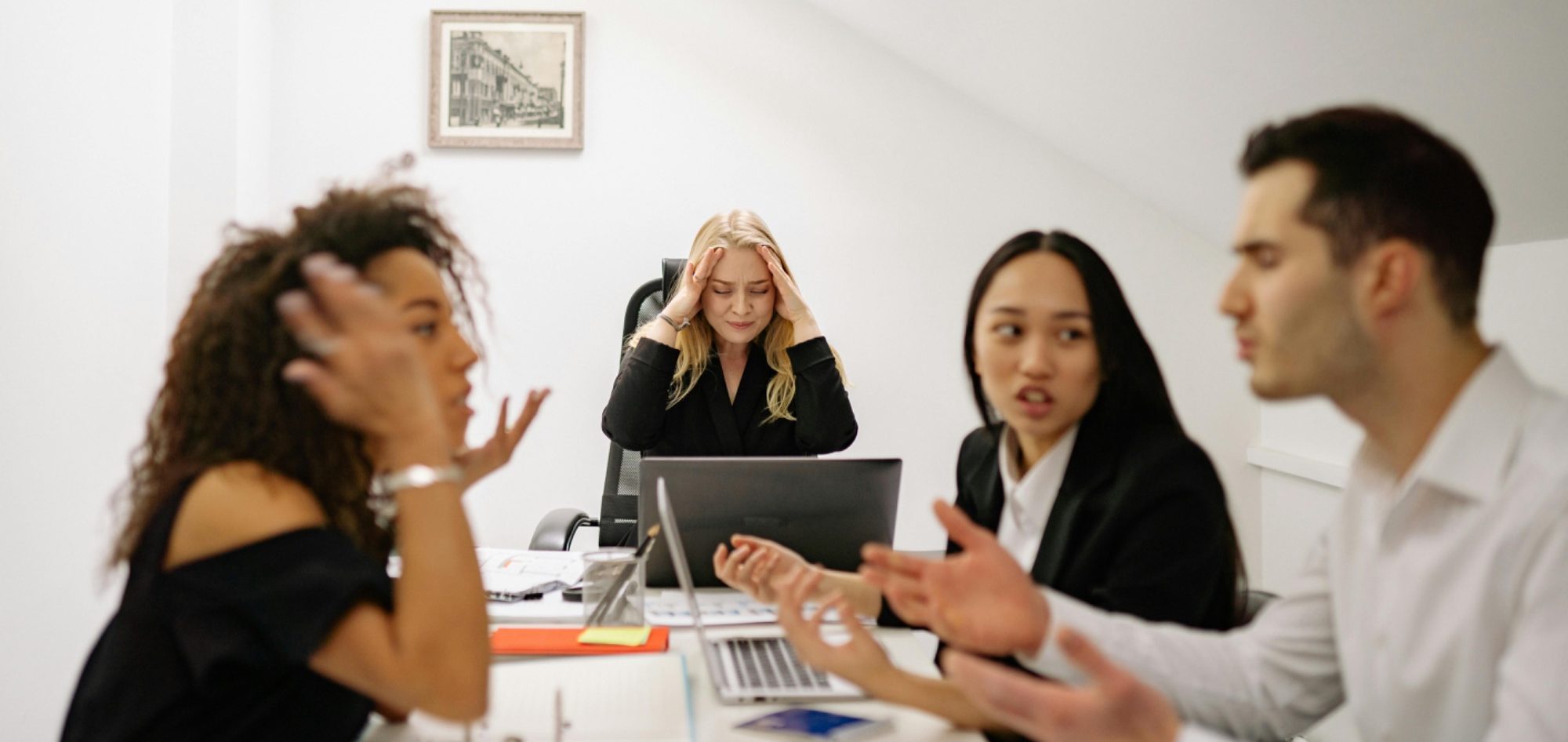 Vier Personen in einem Meeting, mit angeregten Diskussionen und unterschiedlichen Meinungen.