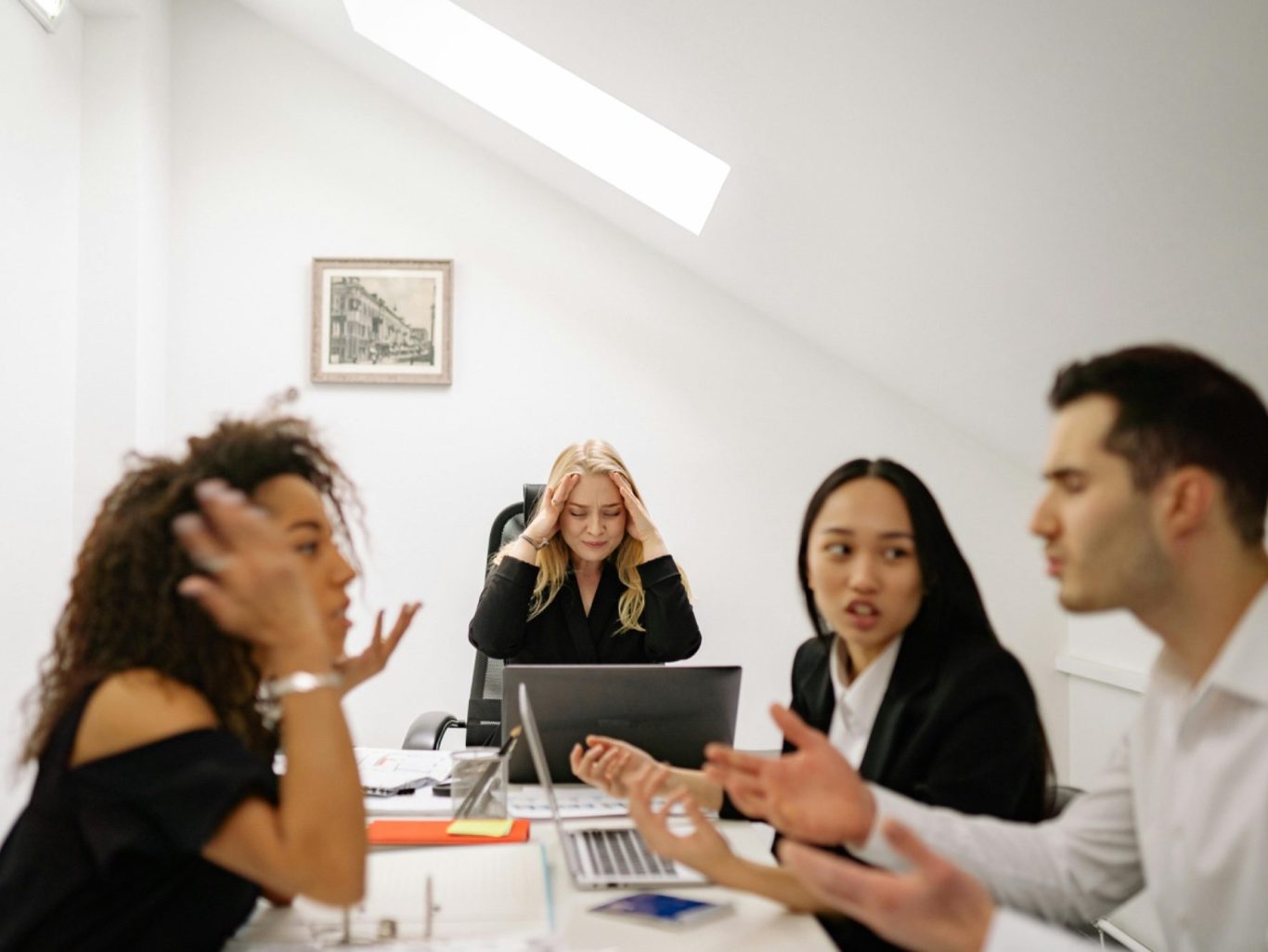 Vier Personen in einem Büro diskutieren angeregt, zwei wirken gestresst.