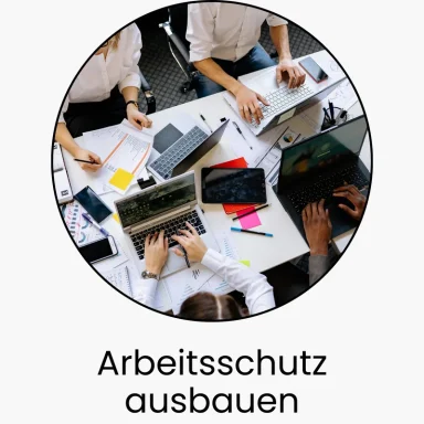 Hände von mehreren Personen, die an einem Tisch mit Laptops und Dokumenten arbeiten.